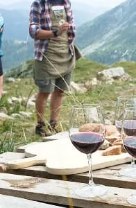 Person on mountain peak with wine and cheese