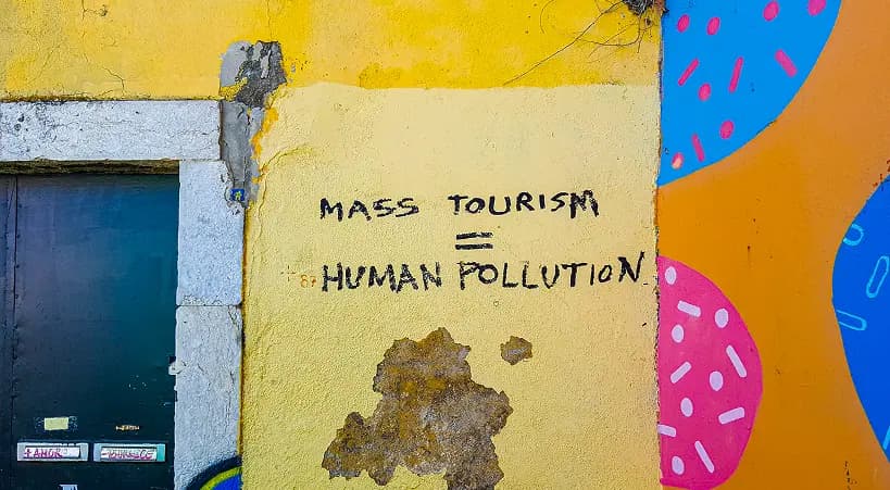 Graffiti wall with text 'MASS TOURISM = HUMAN POLLUTION'